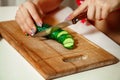 Closeup photo of woman sliced cucumber on a cutting board