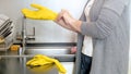 Closeup photo of young housewife in yellow protective gloves on kitchen Royalty Free Stock Photo