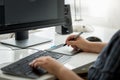 Closeup image of young man designer siting behind computer and working with graphic tablet Royalty Free Stock Photo