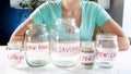 Closeup photo of young woman and different glass jars for investing money
