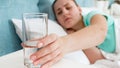 Closeup image of young woman feeling unwell taking glass of water from bedside table Royalty Free Stock Photo