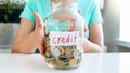 Closeup image of young woman holding glass jar with lots of coins