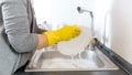 Closeup image of young woman in latex protective gloves washing dishes under water Royalty Free Stock Photo