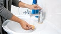 Closeup photo of young woman pouring water on yellow sponge before doing cleanup Royalty Free Stock Photo