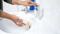 Closeup photo of young woman soaking sponge with water and detergent Royalty Free Stock Photo