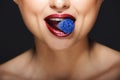 Closeup picture of cheerful girl`s lips holding sweeties with teeth