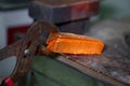 Closeup picture of ingots of melt gold, hot shiny metal bars on table and fire furnace on background