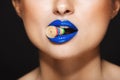 Closeup picture of woman`s colorful lips holding sweeties with teeth. Over grey background