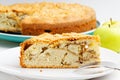 Closeup piece of apple pie with almond petals on white wooden table.