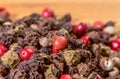 Closeup of a pile of colored peppercorns on a bamboo cutting board. Macro shot. Narrow depth of field.