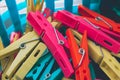 Closeup of a pile of colorful clothes pegs in a blue plastic bucket with holes