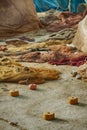 Closeup of a pile of fishing nets with a white rope and red and white cork floats in a fishing port