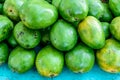 Closeup of pile of green mangoes on turquoise table