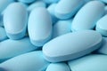 Closeup pile of light blue oval shaped pills with selective focus