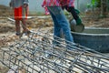 Closeup pile of reinforcement steelwork on the ground at the construction site with blurred workers carrying the bucket of mixed Royalty Free Stock Photo