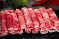 Closeup of a pile of thinly sliced rolled raw meat for hot pot