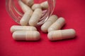 pills falling from transparent container on red backg Royalty Free Stock Photo