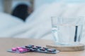 Closeup on pills and glass of water on table and Asian men sleep sick on bed Royalty Free Stock Photo