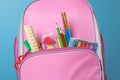 Closeup of pink backpack with office supplies against a blue background. Back to school. The concept of education Royalty Free Stock Photo