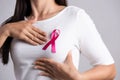 Closeup of pink badge ribbon on woman chest to support breast cancer cause. Healthcare, medicine and breast cancer awareness Royalty Free Stock Photo