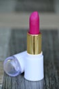 closeup the pink color lipstick golden tube with white cap soft focus natural grey brown background