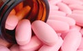 Closeup pink oval shaped pills scattered from the glass bottle