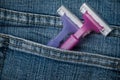 Pink and purple disposable plastic razors in blue jeans pocket Royalty Free Stock Photo