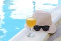 Closeup of pink straw hat and black protective sunglasses, goggles, fresh orange juice smoothie drink cocktail on hotel swimming Royalty Free Stock Photo