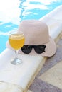 Closeup of pink straw hat and black protective sunglasses, goggles, fresh orange juice smoothie drink cocktail on hotel swimming Royalty Free Stock Photo