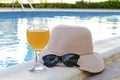 Closeup of pink straw hat and black protective sunglasses, goggles, fresh orange juice smoothie drink cocktail on hotel swimming Royalty Free Stock Photo