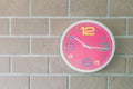 Closeup pink wall clock on brick wall textured background