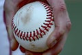 closeup of pitchers hand gripping baseball with seams visible