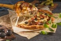 Closeup pizza with bacon, basil, olives, pickles and mozzarella cheese on parchment paper on a dark background. Delicious fresh Royalty Free Stock Photo