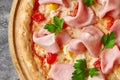 Closeup of pizza with mozzarella, ham slices, quail eggs, tomatoes and greens on wooden serving board Royalty Free Stock Photo
