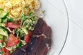 Closeup plate with complete diet meal. Slice of smoked meat, vegetable salad, microgreens, sprouts of cereals, broccoli, tomatoes,