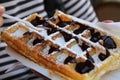 Closeup of a plate of waffles dusted with powdered sugar and drizzled in chocolate ganache