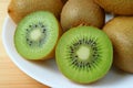 Closeup a plate of whole fruits and cross-sections of fresh ripe kiwi fruits Royalty Free Stock Photo