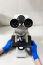 Close up point of view of laboratory assistant looking through microscope lens