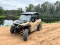 Closeup of a Polaris General in the sand by a river