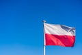 Closeup of the Polish Flag on a flagpole under the sunlight and a blue sky Royalty Free Stock Photo