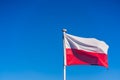 Closeup of the Polish Flag on a flagpole under the sunlight and a blue sky Royalty Free Stock Photo