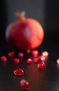 Closeup pomegranate seeds and pomegranate fruit in the background on a dark. Selective focus Contrast