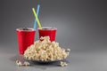 Closeup popcorn on the background of red plastic cups with fizzy drink with colored straws Royalty Free Stock Photo