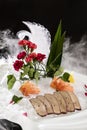 Closeup of pork liver cooked slices on crushed ice and salmon with decorative leaves and flowers