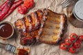 Closeup of pork ribs grilled with BBQ sauce and caramelized in honey on a paper. Tasty snack to beer. Top view. flat lay