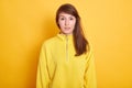 Closeup portrait of adorable dark haired woman wearing yellow hoody, female looking at camera with serious facial expression, Royalty Free Stock Photo