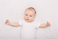 Adorable funny white Caucasian baby with blue grey eyes lying on bed