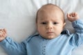 Closeup Portrait Of Adorable Newborn Baby In Blue Bodysuit Lying On Bed Royalty Free Stock Photo