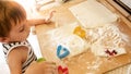 Closeup portrait of adorable 3 years old toddler boy baking cookies and rolling dough with wooden rooling pin. Little Royalty Free Stock Photo