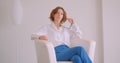 Closeup portrait of adult redhead caucasian businesswoman looking at camera holding glasses with thoughtfulness sitting